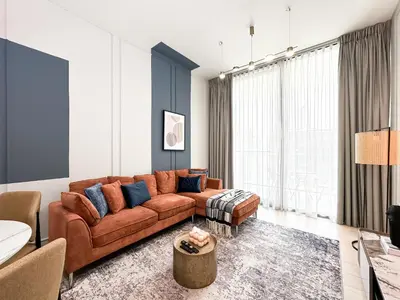 a living room with a brown leather couch at Trophy - Stardust Sanctum Suites w Pool view in Heart of JVC in Dubai