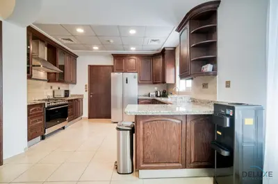 a kitchen with wooden cabinets and a refrigerator at Luxury 3BR Villa with Assistant Room at Alvorada 4 Arabian Ranches by Deluxe Holiday Homes in Dubai