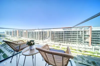 a balcony with chairs and a table and a large building at Sizeable 1BR at Azizi Riviera 35, Al Merkadh by Deluxe Holiday Homes in Dubai
