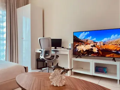 a living room with a flat screen tv and a desk at Full sea view with balcony - Studio Apartment - 10 min to JBR - in Dubai