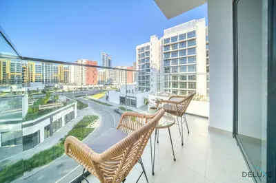a balcony with three chairs and a table on a building at Ravishing 2BR at Azizi Riviera 30, Al Merkadh by Deluxe Holiday Homes in Dubai