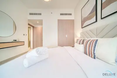 a bedroom with a large white bed with towels on it at Ravishing 2BR at Azizi Riviera 30, Al Merkadh by Deluxe Holiday Homes in Dubai