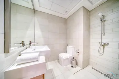 a white bathroom with a sink and a toilet at Ravishing 2BR at Azizi Riviera 30, Al Merkadh by Deluxe Holiday Homes in Dubai