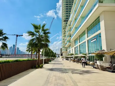 a sidewalk in front of a building with palm trees at Pleasant 1BD apartment with the beach access in Dubai