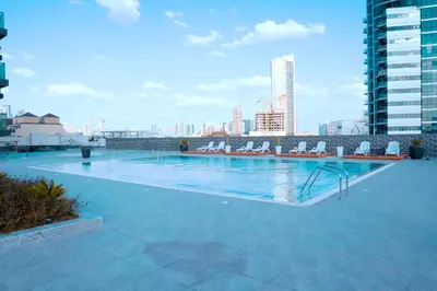 a large swimming pool with chairs and a city skyline at Stylish 1 Bedroom With Amazing View in Dubai