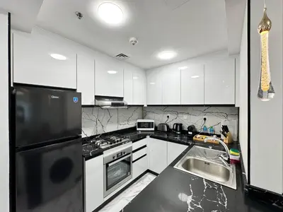 a kitchen with white cabinets and a black refrigerator at Stay in heart of Dubai Marina walk to JBR beach 8 in Dubai