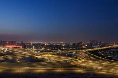 a night view of a freeway interchange with a city at Studion In Dubailand - Close Kitchen in Dubai