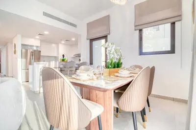 a kitchen and dining room with a wooden table and chairs at Luxury Madinat Living 2BR with Sea Views in Dubai