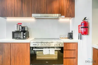 a kitchen with a stove and a red fire extinguisher at Magnificent 2BR at La Voile Jumeirah by Deluxe Holiday Homes in Dubai