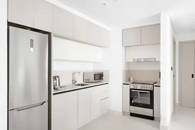 a white kitchen with white cabinets and a refrigerator at Silkhaus Ultra Luxury 1BDR with Sea View in Dubai