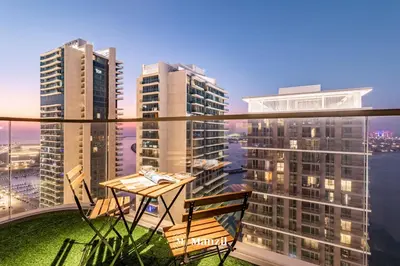 a balcony with a table and chairs and buildings at Manzil - 1BR Apartment in Emaar Beachfront with Private Beach & Marina Access in Dubai