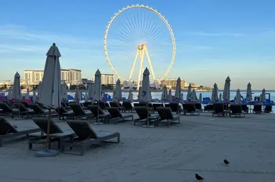a beach with chairs and a ferris wheel in the background at FavDubai presents 2BR apartment in The Heart of JBR and Dubai Marina 150 m to JBR Beach with famous Ain Dubai view the biggest ferris wheel in the world Swimming pool access, air-conditioned gym, free parking & Housekeeping in Dubai