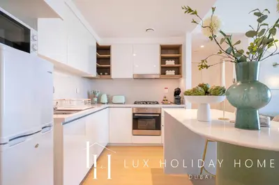 a kitchen with white cabinets and a vase with flowers at LUX The Downtown Zabeel View Suite 2 in Dubai