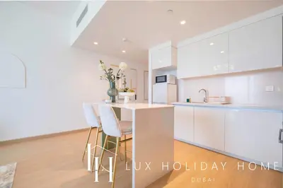 a kitchen with white cabinets and a kitchen island with stools at LUX The Downtown Zabeel View Suite 2 in Dubai