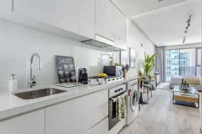 a white kitchen with a sink and a stove at Frank Porter - Ahad Residences in Dubai