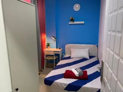 a small room with a bed with a blue wall at Nicest Partition Room in Barsha Heights Near Internet City Metro in Dubai