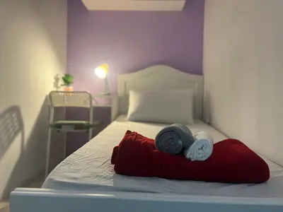 a bed with a red pillow and towels on it at Seperate Partition Room in Tecom / Barsha Heights in Dubai