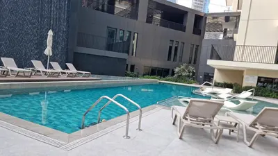 a swimming pool with lounge chairs next to a building at Ahad Residence Walking Distance to Dubai Mall in Dubai
