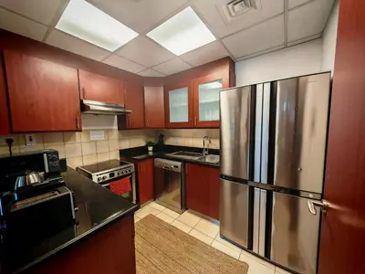 a kitchen with wooden cabinets and a stainless steel refrigerator at Spacious 2BR Apt on JBR Beach near Mall & Metro By La Buena Vida Holiday Homes in Dubai