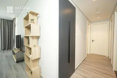 a hallway with a wooden book shelf next to a door at Mira Holiday Homes - Spacious 2 bedroom in Midtown in Dubai