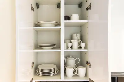 a cupboard filled with white dishes and plates at Seaview & Marina View Studio in Dubai
