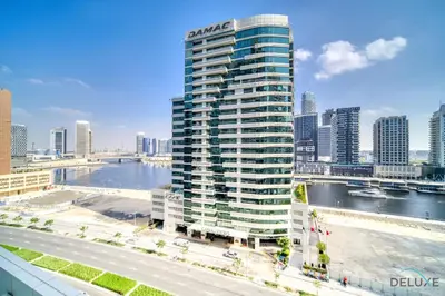 a tall building next to a river in a city at Special Deal Contemporary 1BR with Canal Views by Deluxe Holiday Homes in Dubai