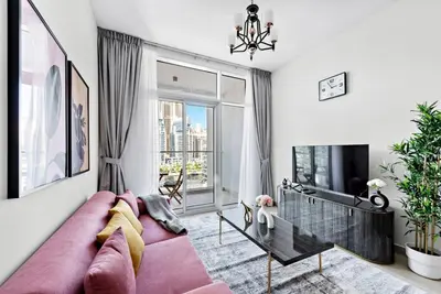 a living room with a pink couch and a large window at StoneTree - Elegant 1BR with Stunning View of Marina in Dubai