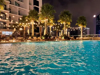 a swimming pool at night with palm trees and lights at Damac Prive l Canal View l Great Location in Dubai