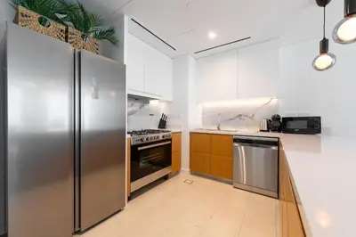 a kitchen with stainless steel appliances and wooden cabinets at LUXSeaside/2BD/LaVie/JBR in Dubai