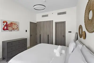 a bedroom with a large white bed and a mirror at Cosy 1BR in the center of JVC in Dubai