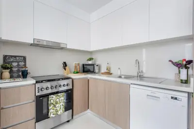 a kitchen with white cabinets and a stove top oven at Frank Porter - The Grand in Dubai