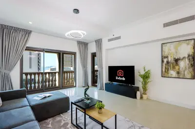 a living room with a couch and a tv at 1BR in Palm Jumeirah, Walk to the Beach and Mall in Dubai