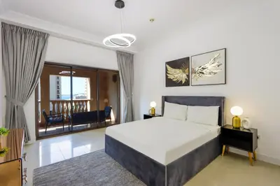 a bedroom with a large bed and a living room at 1BR in Palm Jumeirah, Walk to the Beach and Mall in Dubai