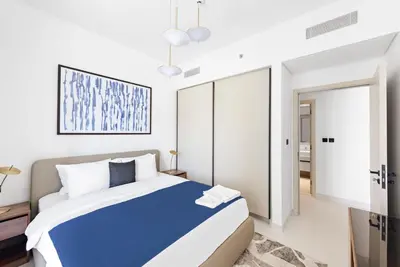 a bedroom with a blue bed in a white room at Silkhaus Marina View with Tower's Private Beach in Dubai