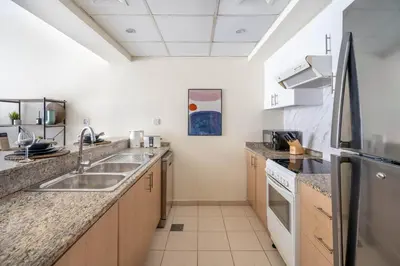 a kitchen with a sink and a refrigerator at GuestReady Holiday Homes - One Mint Sunset in Dubai