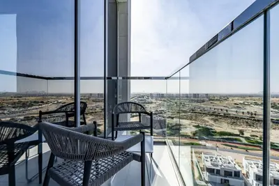 a balcony with chairs and a view of a city at Residence 12 I District One I 1 Bedroom Apartment in Dubai