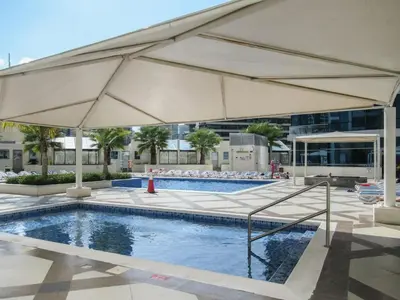 a pool with a large umbrella next to a building at GuestReady - Comfort Stay l Close To Marina Mall in Dubai