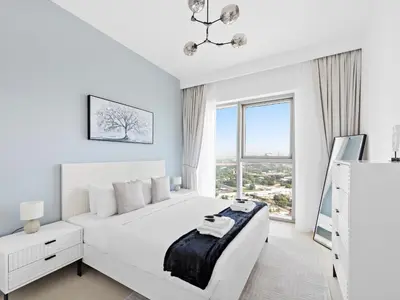 a white bedroom with a bed and a large window at Brand New Elegant 1BDR Direct Access to Dubai Mall in Dubai