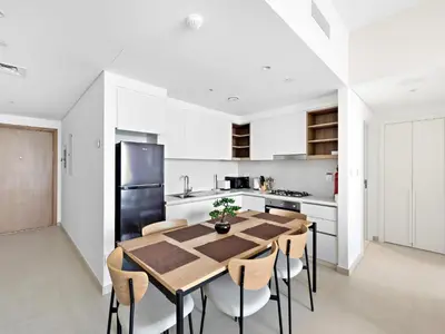a white kitchen with a wooden table and chairs at Brand New Elegant 1BDR Direct Access to Dubai Mall in Dubai