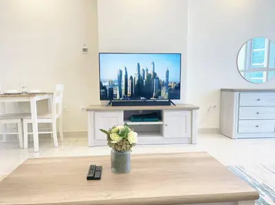 a living room with a tv and a vase of flowers at RH- Beautiful Canal View, Cozy studio near metro station in Dubai