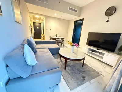 a living room with a blue couch and a tv at StoneTree - Cozy and Modern 1 BR in Dubai