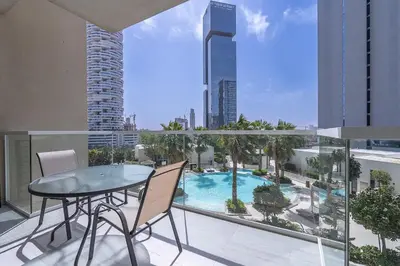 a balcony with a table and chairs and a swimming pool at Luxury & Stylish Studio - JVC in Dubai