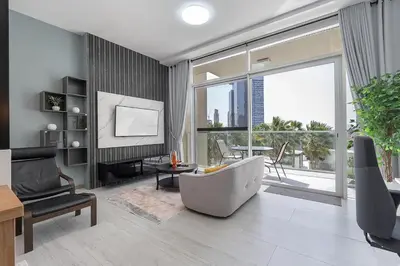 a living room with a couch and a tv and a large window at Luxury & Stylish Studio - JVC in Dubai