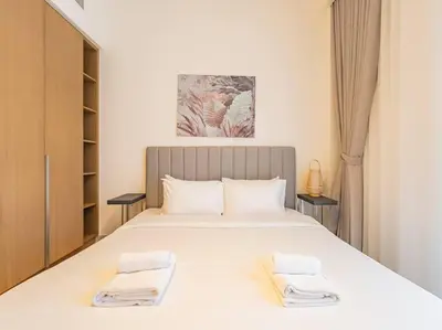 a bedroom with a large white bed with towels on it at Coastal Charm Casita : 1BR Creek Beach Elegance in Dubai