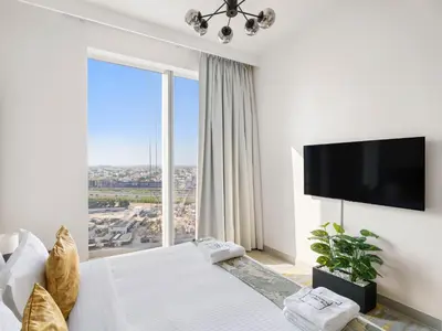 a white bedroom with a large window and a flat screen tv at Sophisticated and Trendy 2BDR In Forte Downtown in Dubai