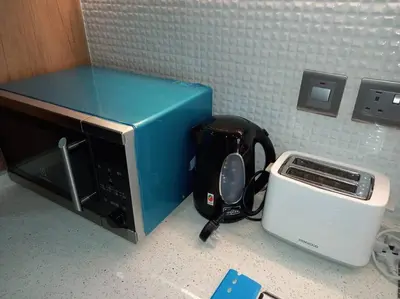 a microwave and a toaster on a kitchen counter at StoneTree - Comfortable Studio in Arjan in Dubai