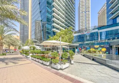 a courtyard with tables and umbrellas in front of buildings at Luxury 1BR Apartment in the heart Marina, Connection to Dubai Marina Mall - Silverene tower in Dubai