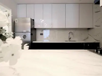 a kitchen with white cabinets and a stainless steel refrigerator at VESTA - Dubai Residence in Dubai