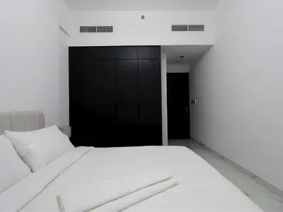 a white bed in a room with a black door at VESTA - Dubai Residence in Dubai