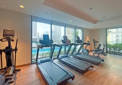 a gym with treadmills and exercise equipment in a room with windows at Lux 1 BD Apartment, 2 Min walk to Dubai Mall & Burj Khalifa - Act One Tower in Dubai